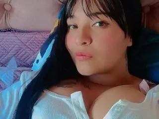 lexxyy26 poses close up, showing her long dark hair and cleavage in a white top.