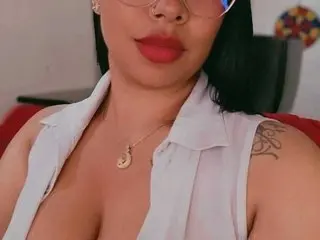loana_bdsm shows off her cleavage and neck wearing a white sleeveless top and a gold necklace, with her dark hair down.
