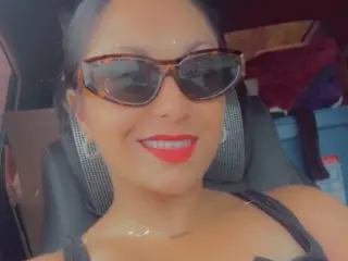 luna_valentina smiles while wearing dark sunglasses and a black tank top inside a vehicle.