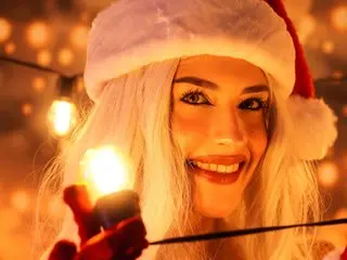 magic_rousse smiles while wearing a white furry hat and showing her long white hair in a warm, glowing setting.