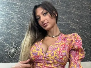 Beautiful woman in a colorful paisley print dress posing against a textured grey wall.