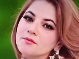 minhaaaaa231 looks at the camera with her light brown hair and dark eye makeup, wearing large white floral earrings.