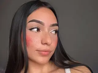 missallydoll_e looks to the side with long black hair and pink blush on her cheeks.