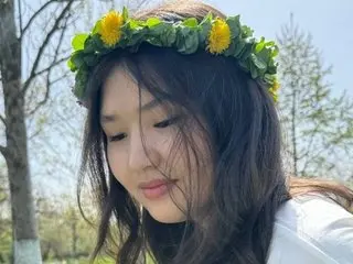 Young woman wearing a yellow flower crown in a sunny spring garden setting with a peaceful mood.