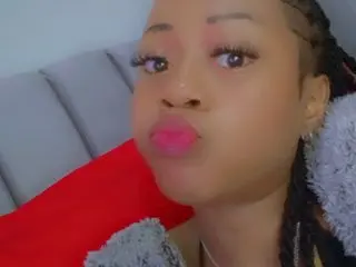 prettywendy20 pouts her lips while looking at the camera, wearing a grey fuzzy top with her hair in long braids.
