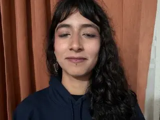 r_galarcio looks at the camera with long, wavy dark hair and a small nose piercing, wearing a dark blue hooded sweatshirt.