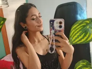 raven_aresx poses for a mirror selfie, wearing a black tank top with her long dark hair down.