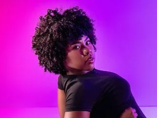 sasshhaaa — sasshhaaa poses with a slight head tilt, wearing a black t-shirt against a purple background.