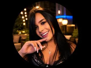 scarletortizz smiles while posing with her long dark hair down, wearing a black lace top or lingerie.