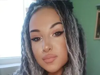 sierra_quinn poses close-up, showing her face, dark eyes, and nose ring with her long, grey-toned dreadlocks framing her face.