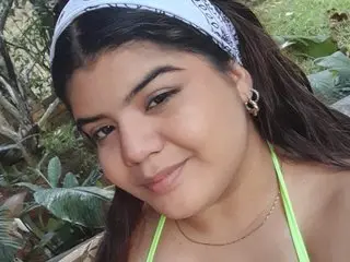 Smiling young woman in a white headband and lime green bikini relaxing in a lush tropical garden.
