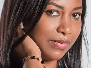 sweetbrown4u21 poses close-up, showing her face and long dark hair with a gold beaded bracelet on her wrist.