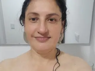 Smiling woman with dark hair in a bright bathroom setting with a natural, relaxed mood.