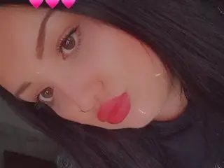 xoPrincessMxo looks into the camera with long dark hair and a close-up view of her face and neck.
