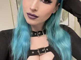 xxxorosa poses with her long blue hair, wearing a black cutout choker top that shows her chest and cleavage.