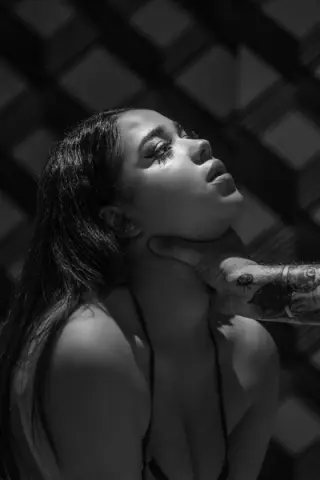 Moody black and white portrait of a young woman in a bikini looking upward in dramatic sunlight.