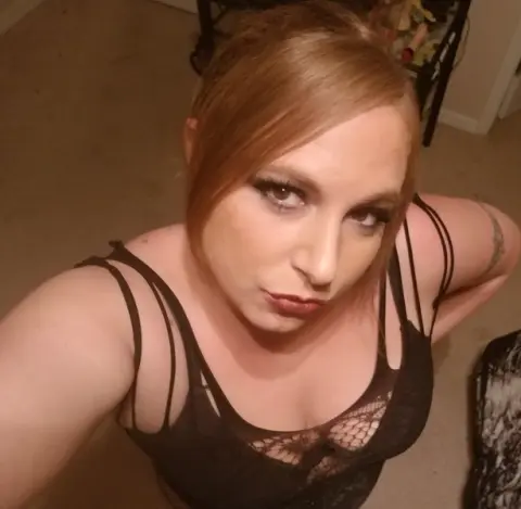 Woman in a black lace camisole top posing indoors with a soft, intimate mood.