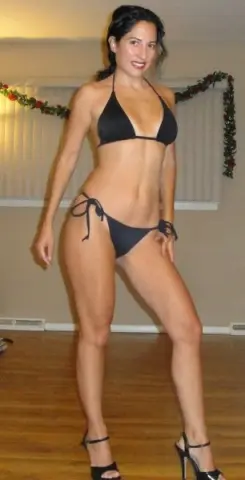 Smiling woman in a black string bikini posing in a bright indoor setting.