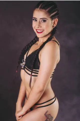 Smiling young woman in black bikini posing against a dark studio background.