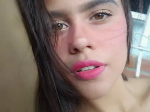 Close-up portrait of a young woman with long dark hair and pink lipstick in soft natural lighting.